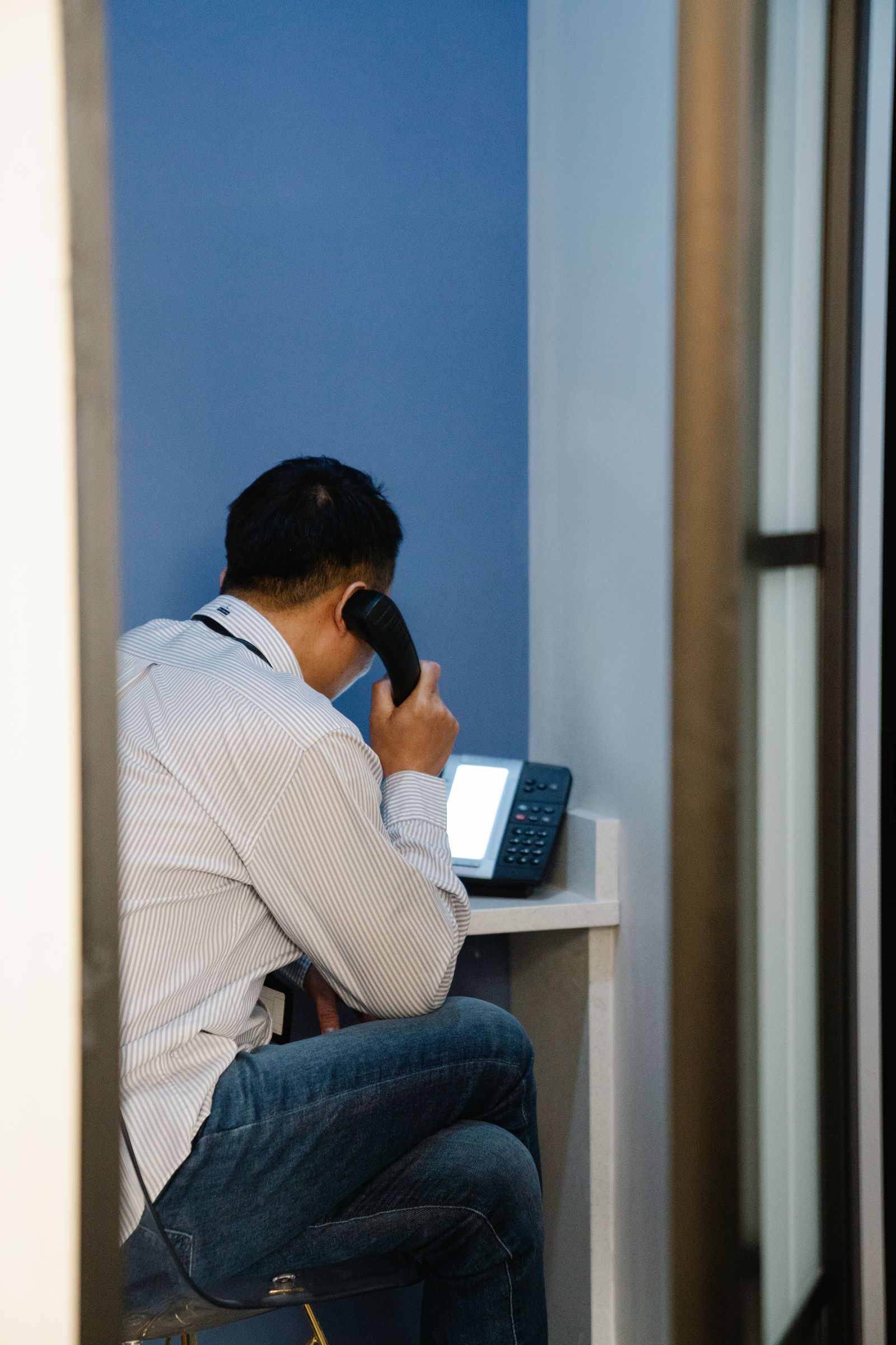 Person on a Yealink-style desk phone in a private office booth